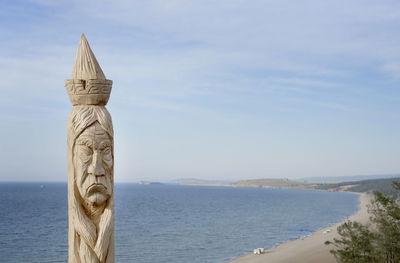 Statue by sea against sky