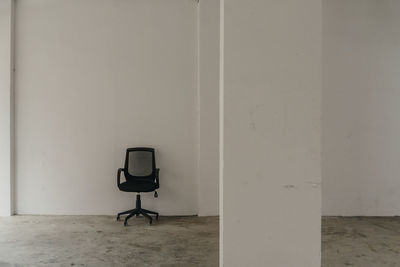 Empty chair against white wall in room