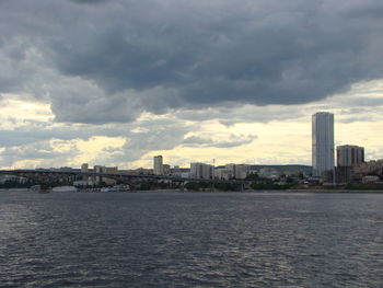 Sea by buildings against sky in city