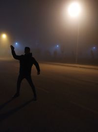 Silhouette man standing on illuminated street at night