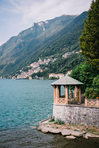 Built structure by sea and mountain against sky