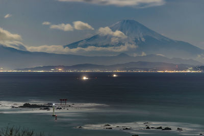 Scenic view of sea by snowcapped mountains against sky