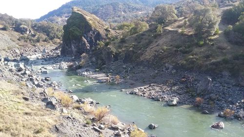 Scenic view of river by mountains against sky