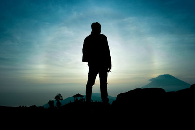 Silhouette of person standing on landscape at sunset