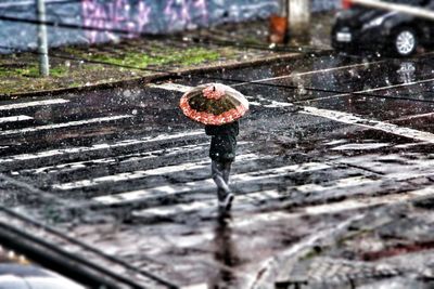 Person with umbrella crossing road during rainfall