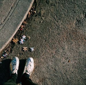 Low section of man standing amidst puzzle pieces on street