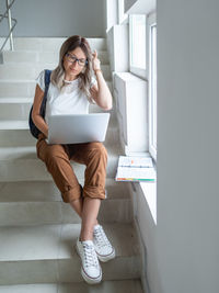 Full length of woman using laptop sitting on steps