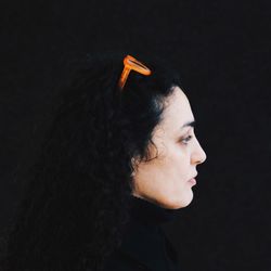 Portrait of young woman looking away over black background