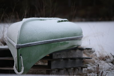 Close-up of snow covered bench on field