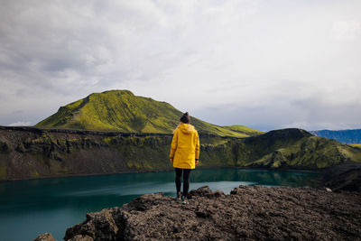 Rear view of man standing on mountain against sky