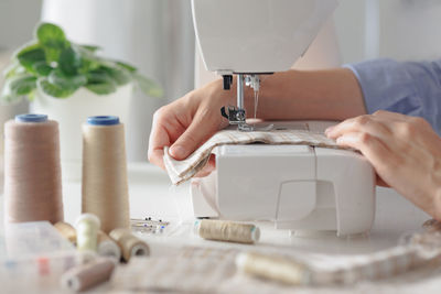 Cropped hands working on sewing machine