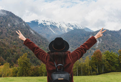 Young woman with outstretched hands, rear view, mountains, adventure.