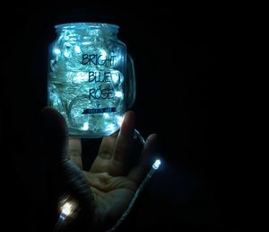 Close-up of hand holding illuminated light against dark background