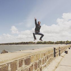 Full length of man jumping on retaining wall