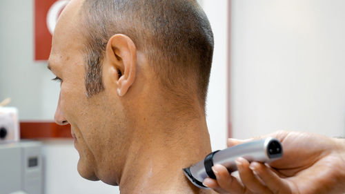 Cropped hand of barber cutting man hair with electric razor