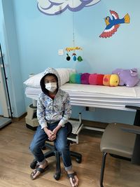 Full length of a boy  sitting on chair at the doctor office.