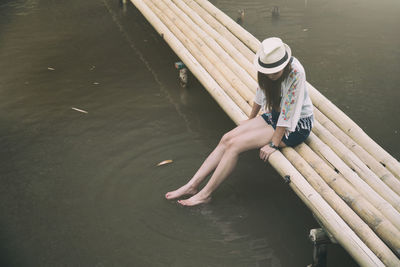 High angle view of young woman relaxing on footbridge over lake