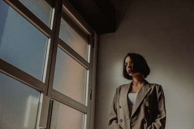 Full length of woman standing against wall