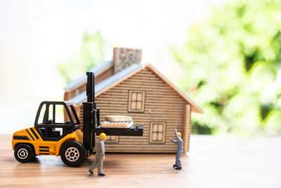 Figurines and construction machinery by model house on table