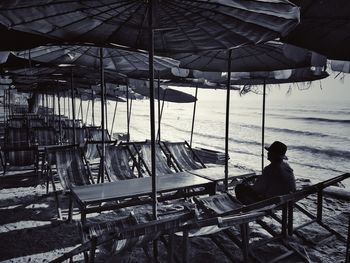 Rear view of man sitting on seat at beach