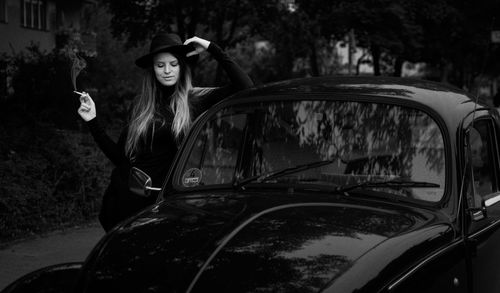 Young woman smoking cigarette by car
