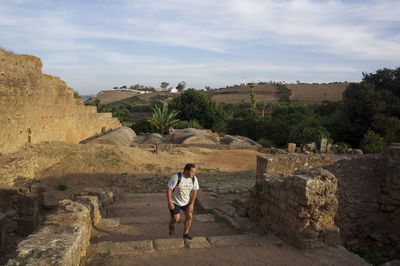 Man on steps at old ruin against sky