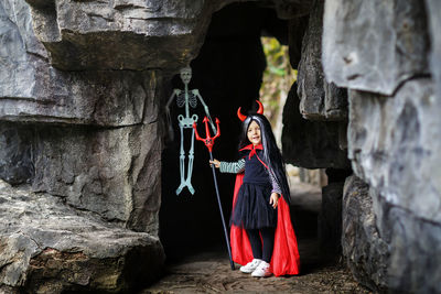 Portrait of cute girl wearing costume standing against rock formation