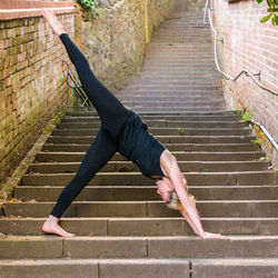 Young woman doing yoga on staircase