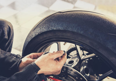 Midsection of man repairing tire of car