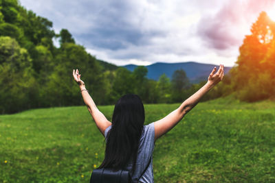 Rear view of woman with arms raised against sky