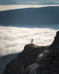 Man standing on cliff against sky