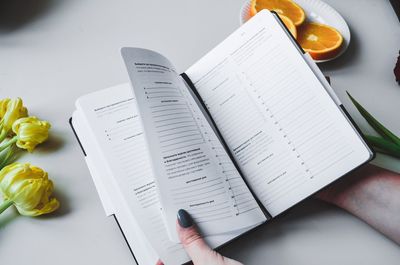 High angle view of hand holding book on table