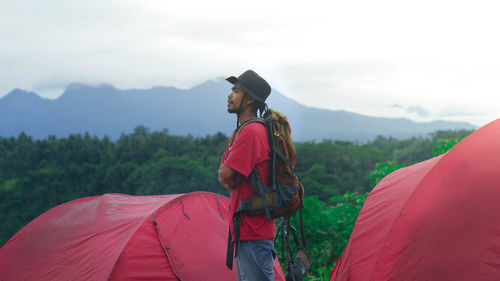 Side view of woman standing on mountain against sky