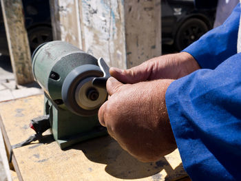 Cropped hands sharping knife on machinery