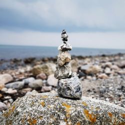 Stack of stones on rock at beach against sky