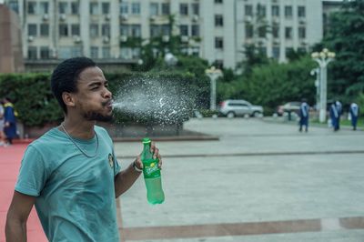 Full length of man drinking water in city