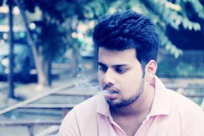 Portrait of young man smoking outdoors
