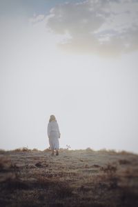 Rear view of man on field against sky