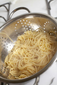 Draining hot, cooked spaghetti noodles in a colander