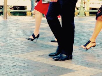 Low section of men walking on sidewalk in city