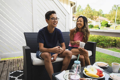 Happy mother and son having snacks sitting on couch at porch