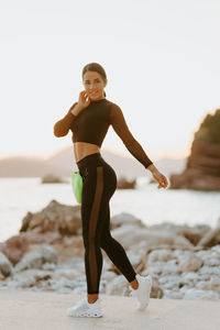 Full length of young woman exercising on beach