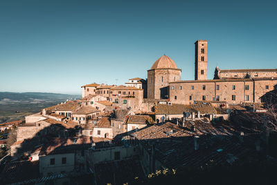 Old buildings in city against clear blue sky