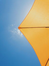 Directly below shot of yellow parasol against blue sky