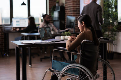 Woman using mobile phone while sitting on table