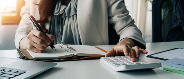 Midsection of businessman working on table