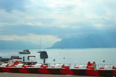 Boats in sea against cloudy sky