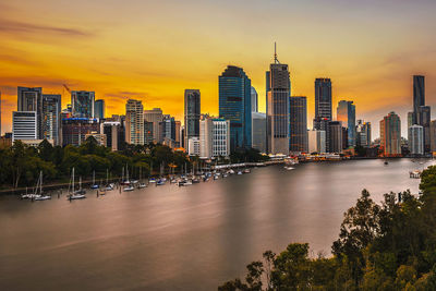 River amidst buildings against sky during sunset