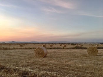 Hay bales on field against sky