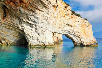 Rock formation by sea against sky